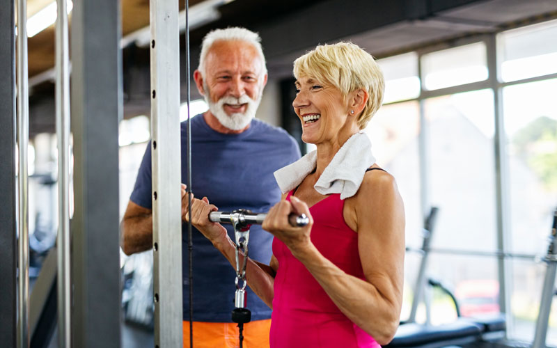 Senior man and woman exercising at the gym, smiling and staying active together.
