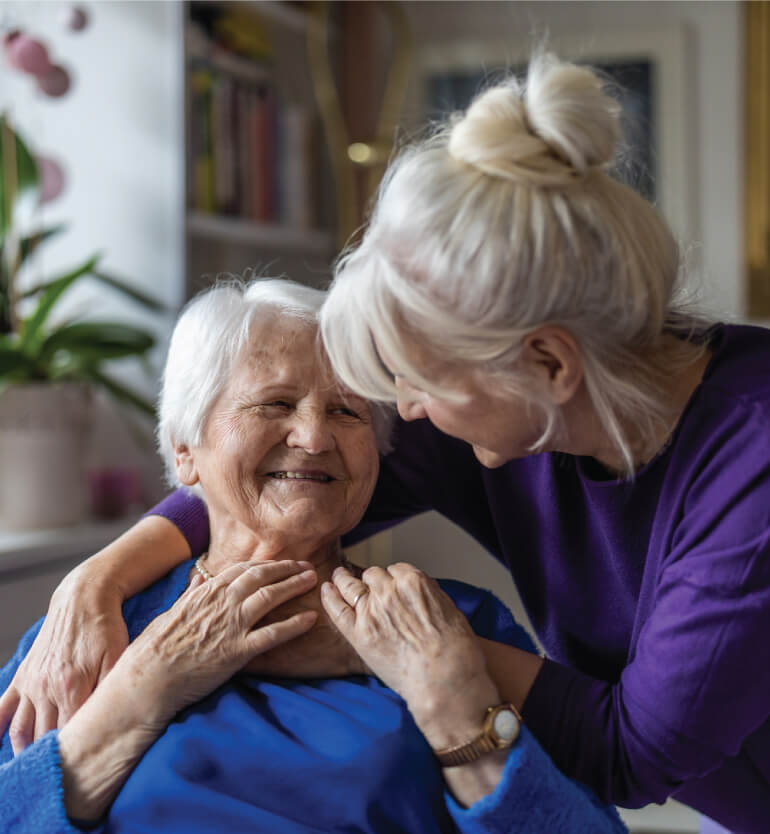 Senior woman receiving a hug from behind from a friend